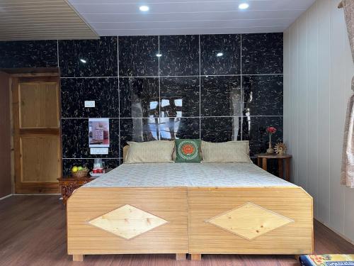 a bedroom with a bed with a black tiled wall at SNOWFLAKE Homestay in Gondla
