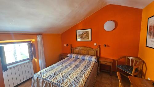 1 dormitorio con paredes de color naranja, 1 cama y ventana en HOSTAL ALBE, en Carrión de los Condes
