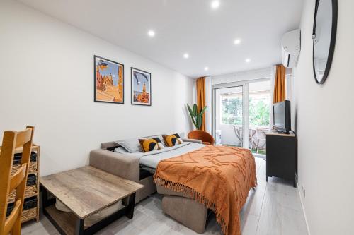 1 dormitorio con cama, sofá y TV en Charmant 2 pièces - Proche plage en Menton