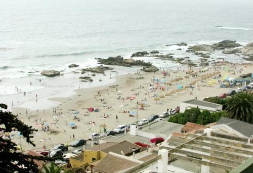 un grupo de personas en una playa con el océano en Depto. Maitencillo 3 dormitorios, 2 estacionamientos, gran terraza frente a la playa, en Valparaíso