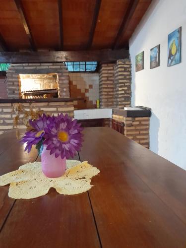 un jarrón con flores púrpuras sentado en una mesa de madera en La casa de Moni, en Areguá
