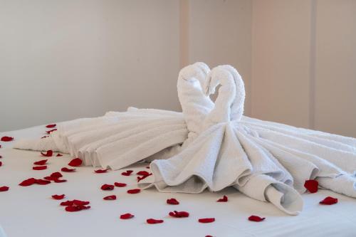 twee zwanen gewikkeld in witte handdoeken op een bed met harten bij Ruellia Luxury Apartments in Lefkada