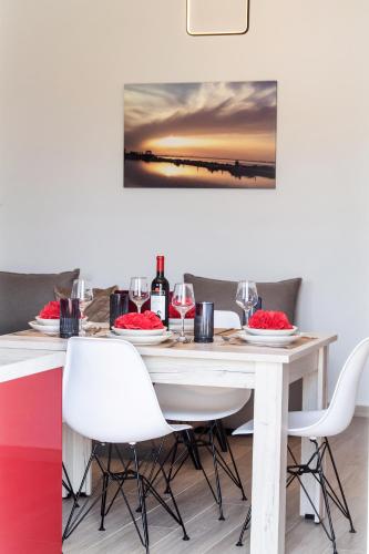 a dining table with white chairs and wine glasses at Ruellia Luxury Apartments in Lefkada Town