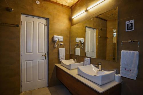 a bathroom with two sinks and a large mirror at Beyond Stay Lall Ji Tourist Resort in Dalhousie
