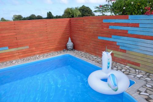 a swimming pool with a float in front of a brick wall at Bungalow La Perle - Jacuzzi - Piscine in Saint-François
