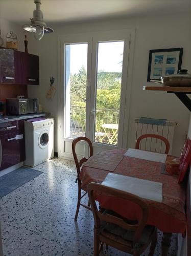 une cuisine avec une table et une machine à laver dans l'établissement Chambre d'hôtes les garrigues, à Piolenc