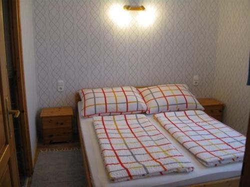 um pequeno quarto com 2 camas e uma luz na parede em Andrea Apartmanház em Balatonlelle