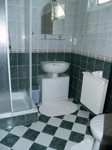 uma casa de banho com um lavatório, um chuveiro e um WC. em Andrea Apartmanház em Balatonlelle