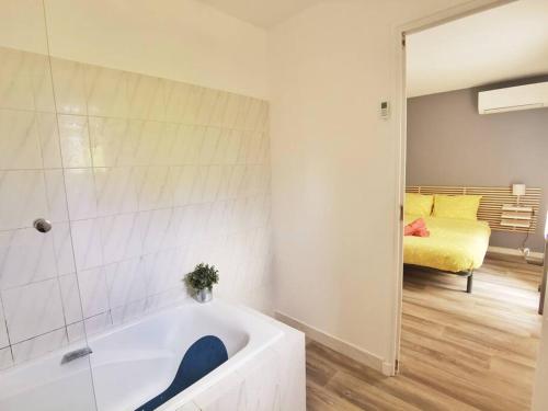 - une salle de bains blanche avec baignoire et une chambre dans l'établissement Les quatre loges - joli t2 jardinet et parking *3, à Aix-en-Provence