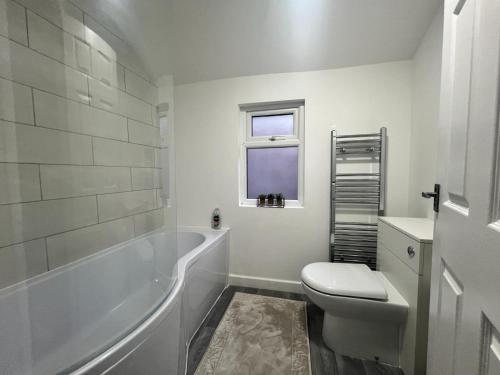 a bathroom with a tub and a toilet and a sink at 4 bedroom, sleeps 8 comfy home near to City Centre and Beaches! in Swansea