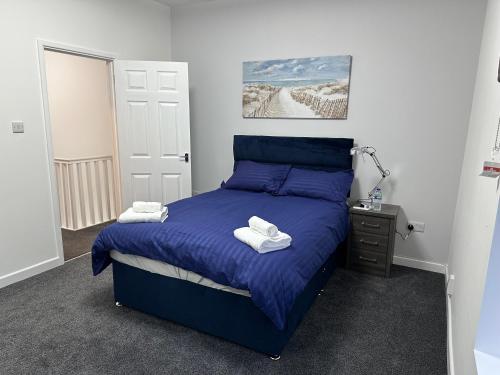 a bedroom with a blue bed with towels on it at 4 bedroom, sleeps 8 comfy home near to City Centre and Beaches! in Swansea