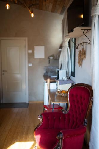 a red chair sitting in a room with a door at Gate Away B&B Units - המקום באל רום in El-Rom