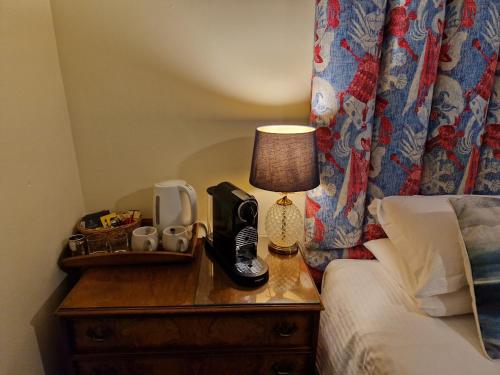 a lamp on a night stand next to a bed at Y Branwen Restaurant & Rooms - Adult Only and Dog Friendly in Harlech
