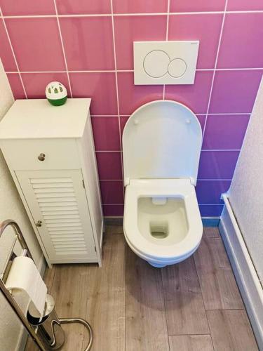 La salle de bains est pourvue de toilettes et d'un mur carrelé rose. dans l'établissement Appartement pour 4 vue sur la marina de Canet, à Canet