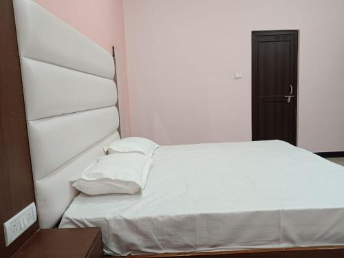 a bed with white sheets and pillows in a room at Holy Homestay in Faizābād