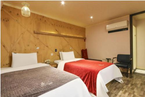 una habitación de hotel con 2 camas y una silla en Dorothy Hotel en Cheonan