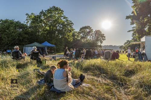 a group of people sitting in the grass in a field at Nysted Strand Camping & Cottages in Nysted