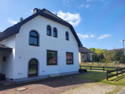 een wit huis met een zwart dak bij Haus am Wald - Haus Nils und Haus Nele in Bark