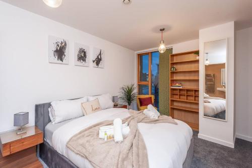 ein Schlafzimmer mit einem großen weißen Bett und einem Spiegel in der Unterkunft Pass the Keys Granary Wharf Deluxe - balcony and rooftop garden in Leeds