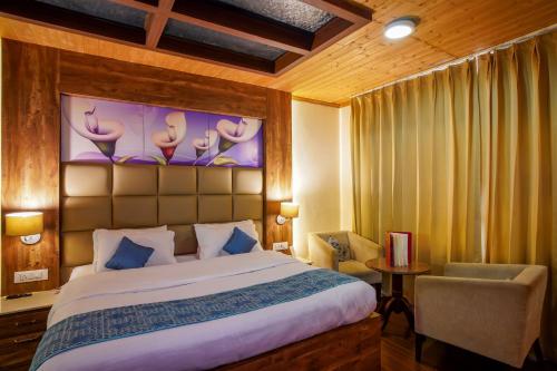 a bedroom with a large bed and a chair at Beyond Stay Lall Ji Tourist Resort in Dalhousie