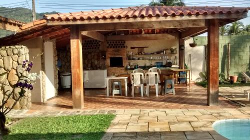 a pavilion with chairs and a kitchen in a backyard at Pousada Na Praia Ubatuba in Ubatuba
