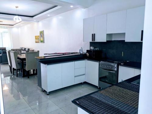 uma cozinha com armários brancos e uma mesa em Homestay in Kigali, Rusororo em Masaka