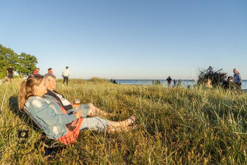 two people sitting in the grass at the beach at Nysted Strand Camping & Cottages in Nysted