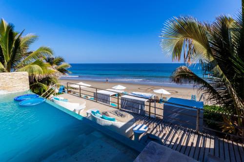 a swimming pool next to a beach with palm trees at DCO Suites Lounge & Spa in Máncora