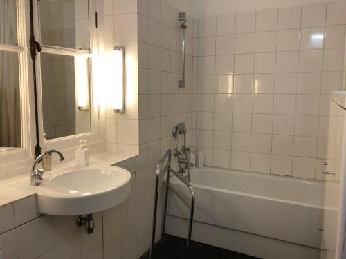 ein weißes Badezimmer mit einem Waschbecken, einer Badewanne und einem Waschbecken in der Unterkunft Beautiful studio in the heart of Le Marais in Paris