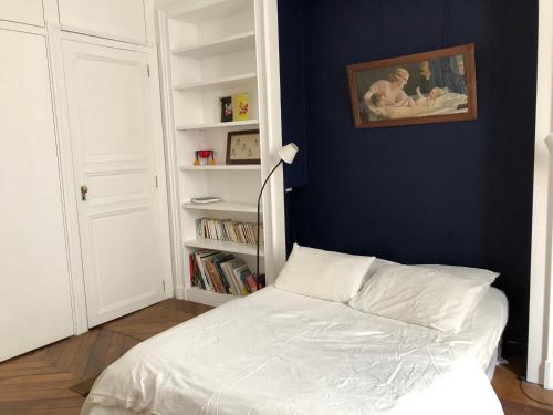 a bedroom with a white bed and a book shelf at Beautiful studio in the heart of Le Marais in Paris