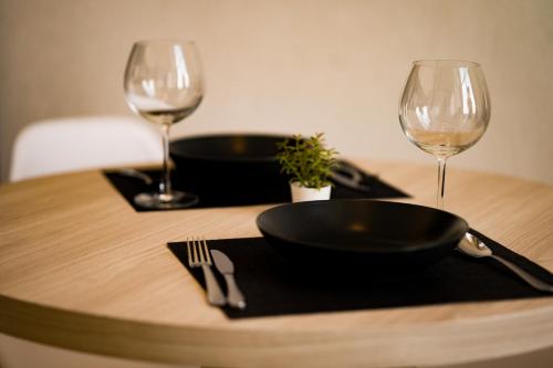 a table with a black plate and two wine glasses at On Nut Duplex with City Views, 5-minute Walk to BTS, Ideal Long Stays in Bangkok