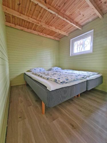 a bed in a green room with a window at Nysted Strand Camping & Cottages in Nysted