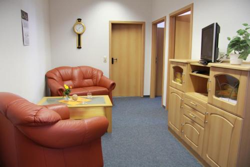 a living room with a couch and a chair and a tv at Pension Take Off in Gera