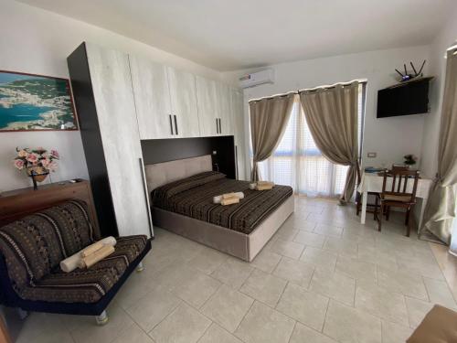 sypialnia z łóżkiem, krzesłem i kanapą w obiekcie Home 105 Salento w mieście Galatone