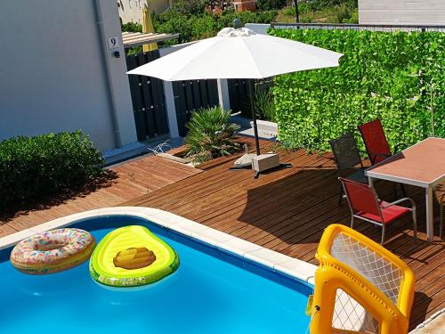 einen Pool mit einem Tisch und einem Sonnenschirm in der Unterkunft Gumla House in Stara Novalja