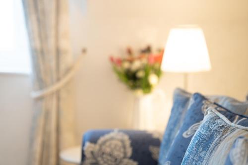 a blue couch with a lamp and a vase of flowers at Barnes Fell Apartments in Ambleside