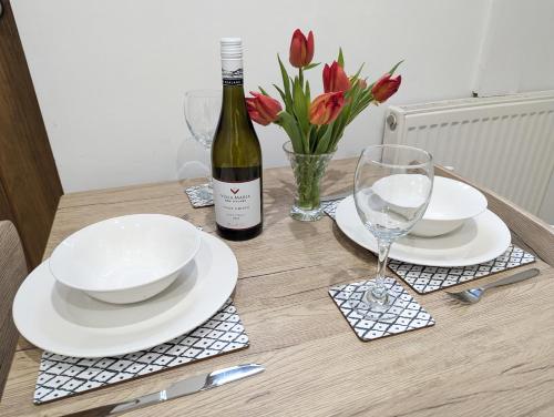 una mesa con platos blancos y una botella de vino en Swan Lake Lodge & free parking, en Cardiff