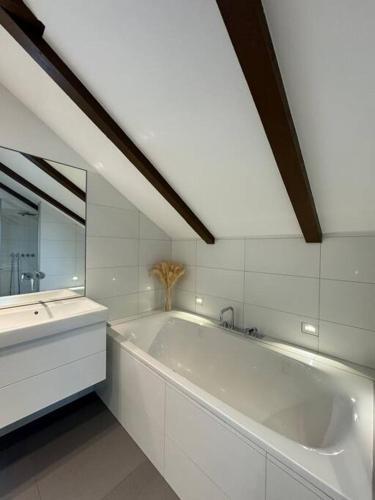 een witte badkamer met een groot bad en een wastafel bij Juwel am Stadtrand von Wien in Korneuburg