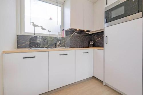 uma cozinha com armários brancos e uma janela em Vakantiehuis Belle em Nieuwpoort