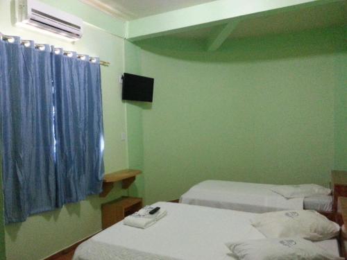 a small room with two beds and a television at Hotel Chalé Ji-Parana in Ji-Paraná