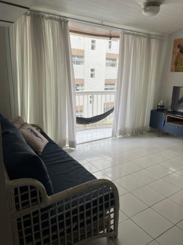 uma sala de estar com uma cama e uma janela grande em Guarujá Flat no Guarujá