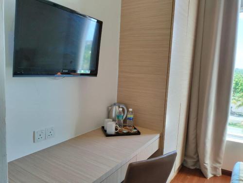 a room with a tv on a wall with a shelf at Sunflower World Hotel in Kuala Selangor
