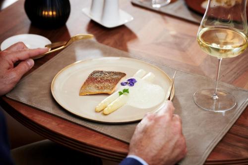 a plate of food on a table with a glass of wine at MalisGarten Green Spa Hotel - Adults Only in Zell am Ziller