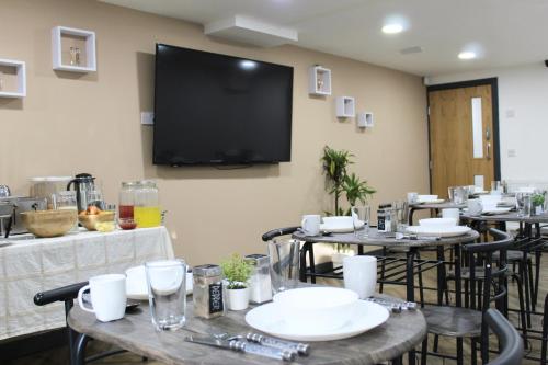 a room with tables and chairs with a television on the wall at Johal Mini Hotel -Birmingham City-FREE BREAKFAST in Birmingham