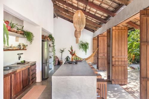 uma cozinha em plano aberto com armários de madeira e uma grande ilha em Casa Canoa - Praia de Algodões em Maraú