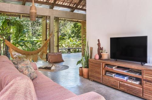 uma sala de estar com um sofá e uma televisão de ecrã plano em Casa Canoa - Praia de Algodões em Maraú
