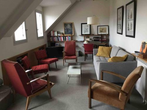 a living room with a couch and red chairs at 2 bedrooms in the sky ! in Neuilly-sur-Seine