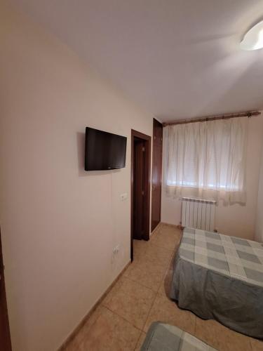 a bedroom with a bed and a flat screen tv on the wall at Hostal Pension - La Rotonda in Tardienta