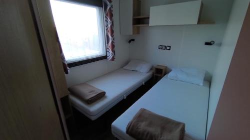 a small room with two beds and a window at MOBILE HOME FOR YOU in Canet-en-Roussillon