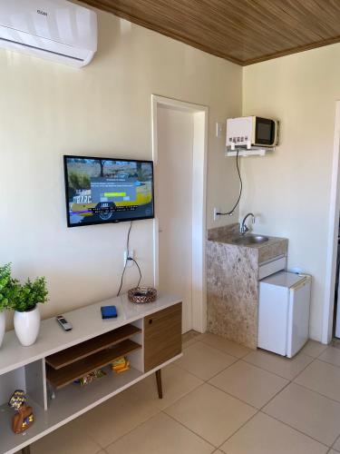 a living room with a tv on the wall at Flat Beira Mar no Condomínio Diver in Vera Cruz de Itaparica